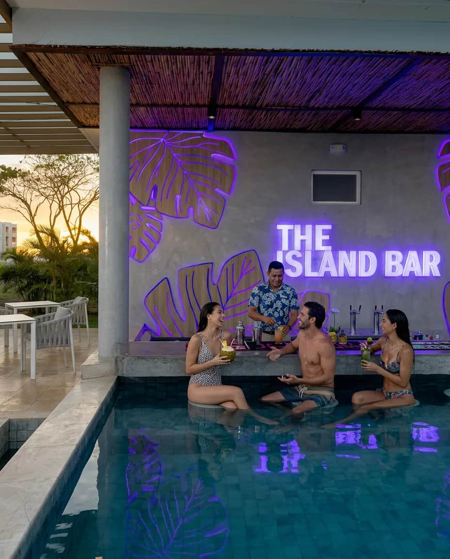 The Island Bar iluminado al atardecer, con huéspedes en la piscina