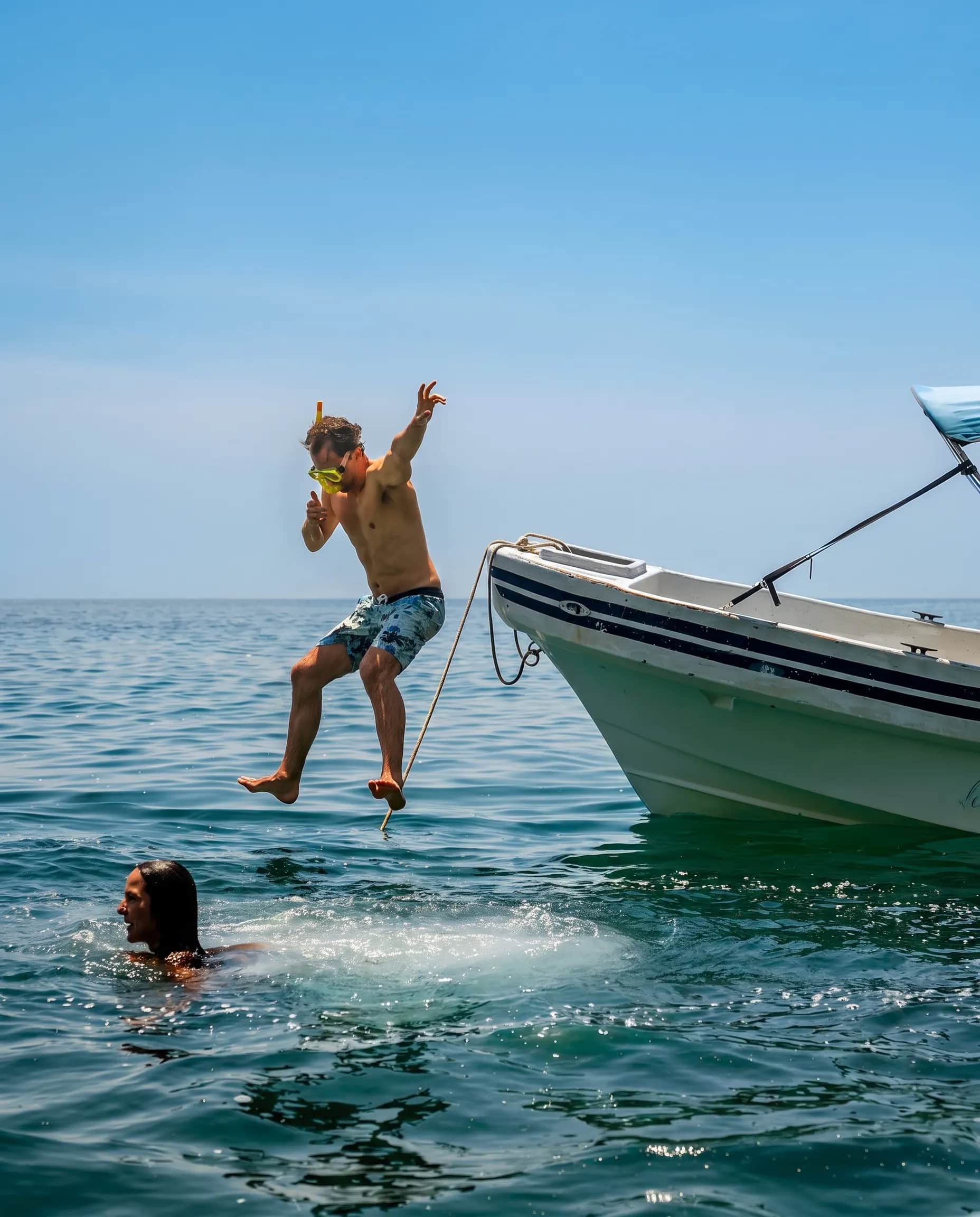 Personas saltando al mar desde una lancha para hacer esnórquel