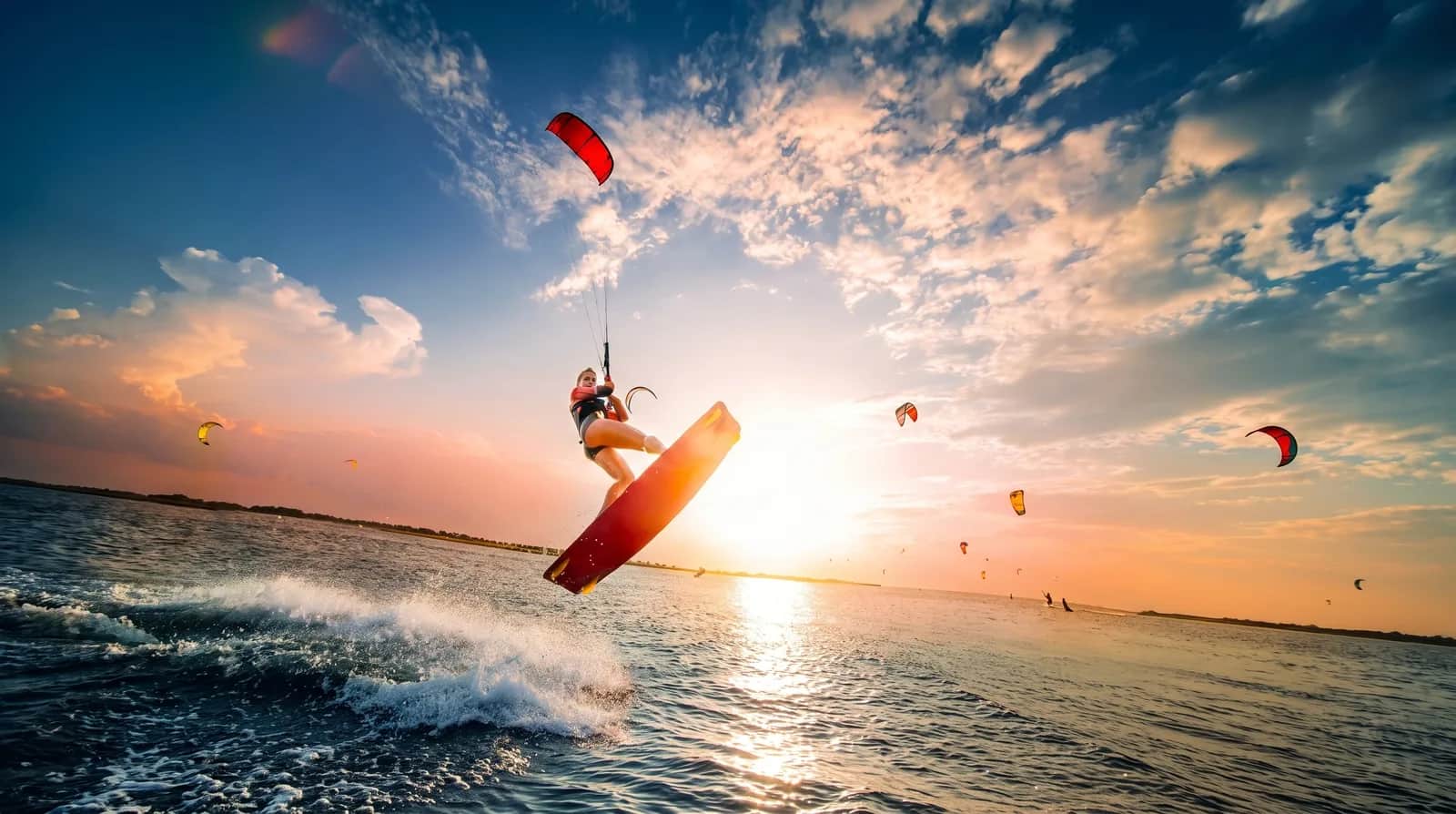 Kitesurfista saltando sobre el agua al atardecer
